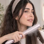 زنی در حال صاف کردن مو با اتو بخار شگلم